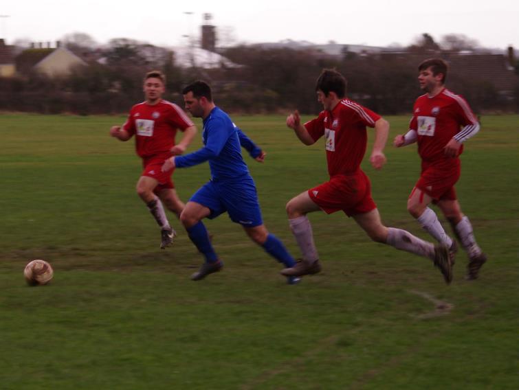 Merlins Bridge striker Steven McNabney takes on Milford United defenders
