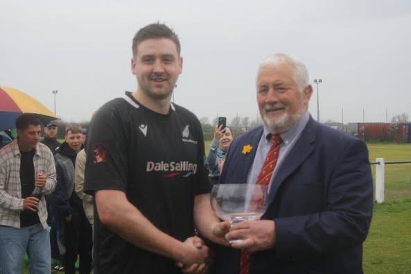 Neyland captain George Williams receives silverware from Anthony Buchanan of the WRU