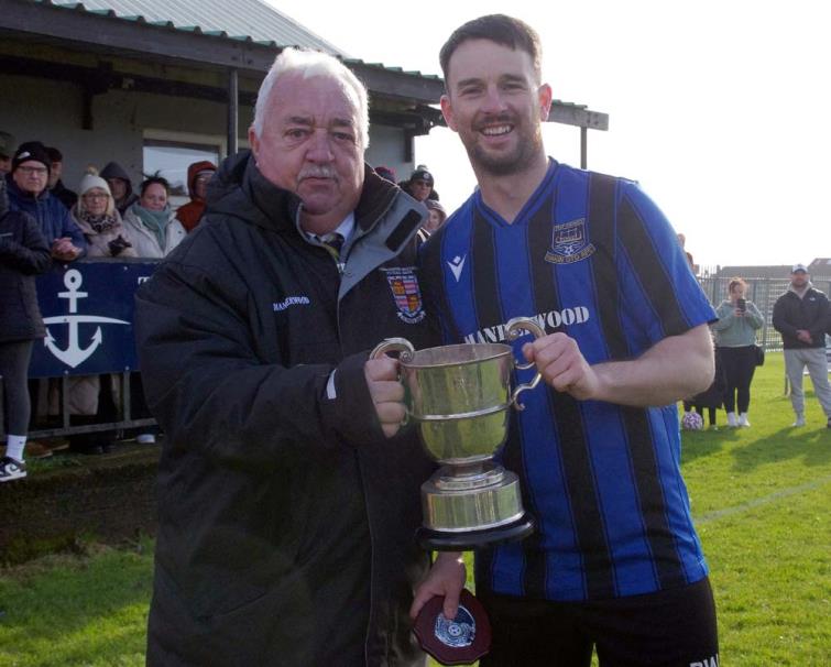 Hakin United skipper receives the Division 1 silverware from League chairperson Mackie Harts.