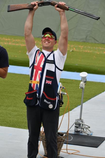 Proudly raises his gun aloft